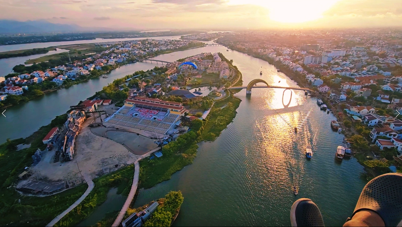 Aerial view of Hoi An Memory Island during sunset, showcasing the open-air theater, walking paths, and surrounding river landscape.