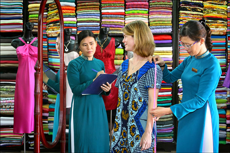 Foreign tourists trying on traditional ao dai dresses at a tailoring shop in Hoi An