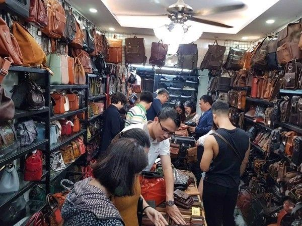 Tourists shopping for handmade leather goods in a traditional Hoi An shop