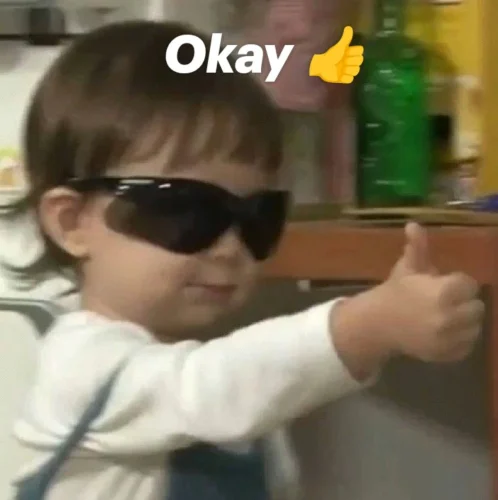 Em bé đeo kính đen giơ ngón cái kèm chữ Okay, kiểu ngầu ra vẻ người lớn